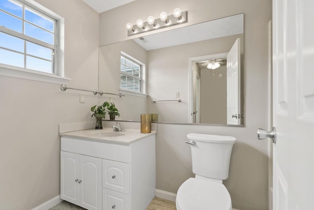 bathroom featuring toilet, baseboards, and vanity