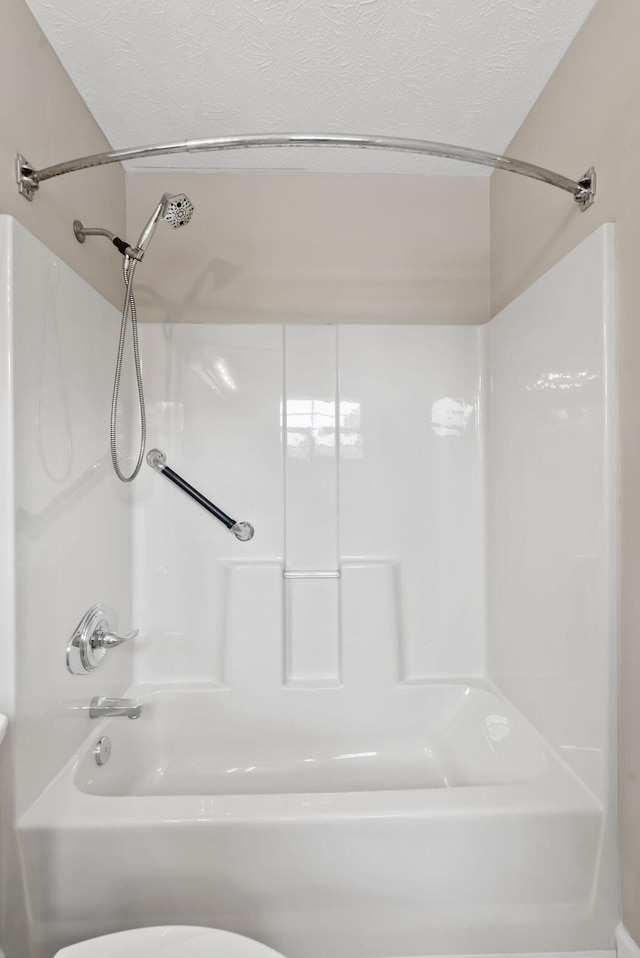bathroom with a textured ceiling, toilet, and  shower combination