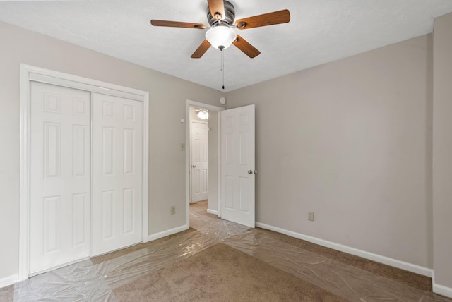 unfurnished bedroom with a closet, baseboards, a ceiling fan, and carpet flooring