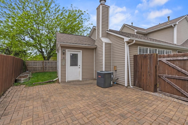 rear view of property featuring a chimney, roof with shingles, a patio area, cooling unit, and a fenced backyard
