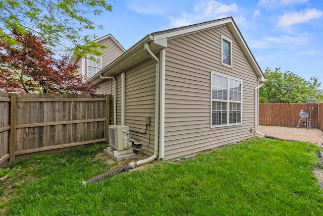 view of side of property featuring a lawn, a patio, ac unit, and a fenced backyard