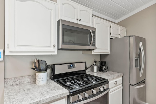kitchen with light countertops, appliances with stainless steel finishes, white cabinets, and ornamental molding