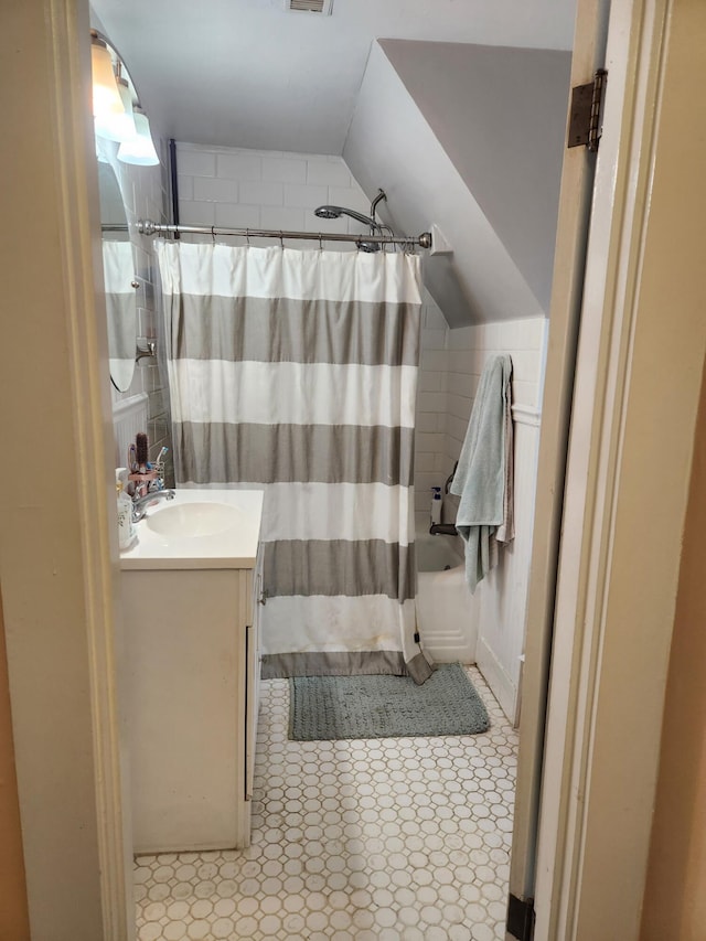 bathroom with tile patterned flooring, visible vents, vanity, vaulted ceiling, and shower / tub combo