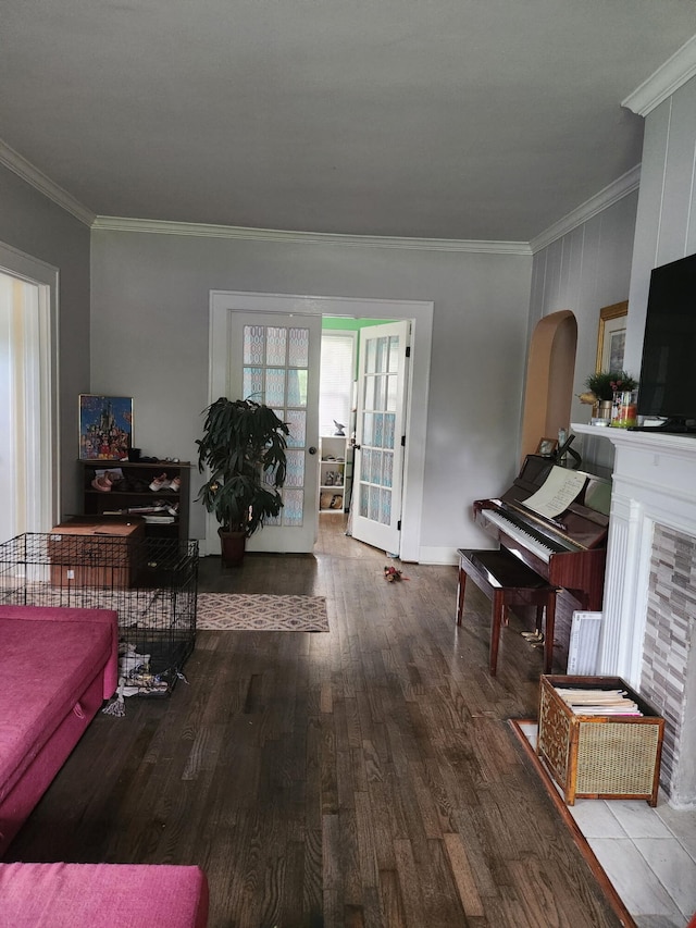 living area featuring arched walkways, baseboards, ornamental molding, and wood finished floors