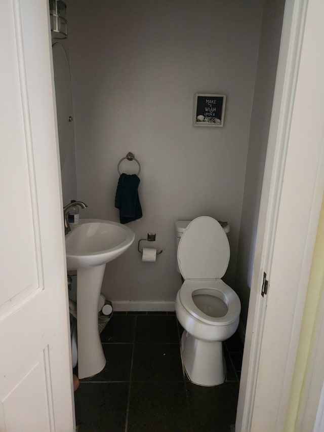 half bath featuring tile patterned floors, baseboards, and toilet