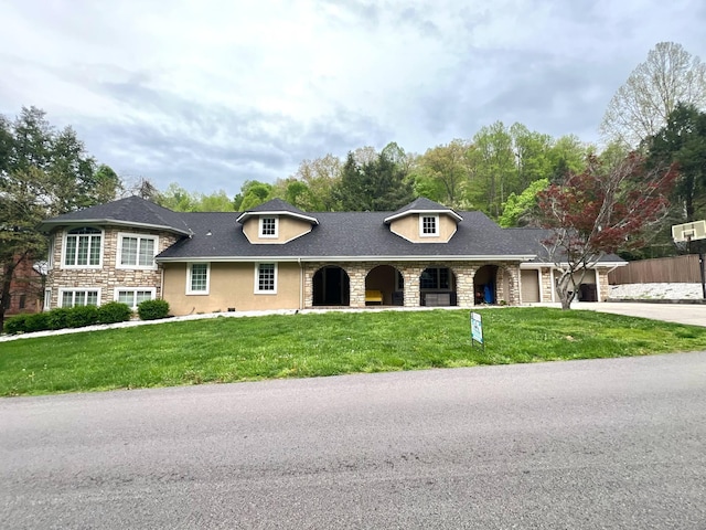 view of front facade featuring concrete driveway, a front yard, and stone siding