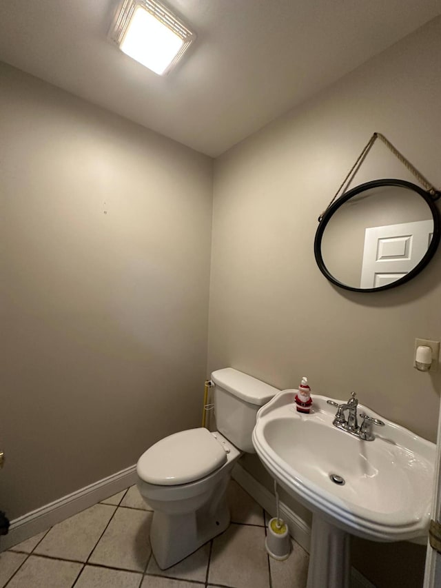 bathroom with a sink, tile patterned floors, baseboards, and toilet