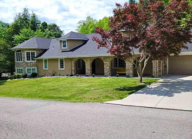view of front of home featuring stone siding, stucco siding, a front yard, concrete driveway, and covered porch