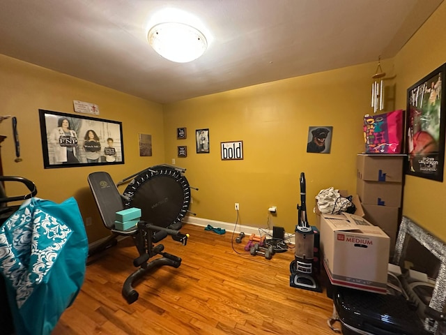 exercise room with baseboards and wood finished floors