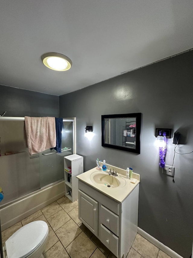 full bath with tile patterned flooring, vanity, baseboards, combined bath / shower with glass door, and toilet