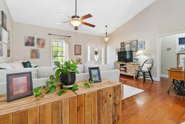 living room with baseboards, a ceiling fan, lofted ceiling, and wood finished floors