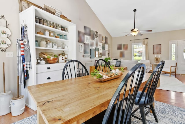 dining space with light wood-type flooring, ceiling fan, and vaulted ceiling