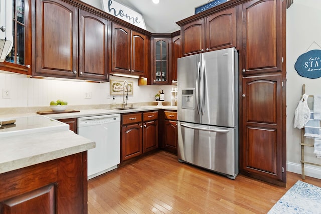 kitchen with stainless steel fridge, white dishwasher, light wood-style floors, and a sink