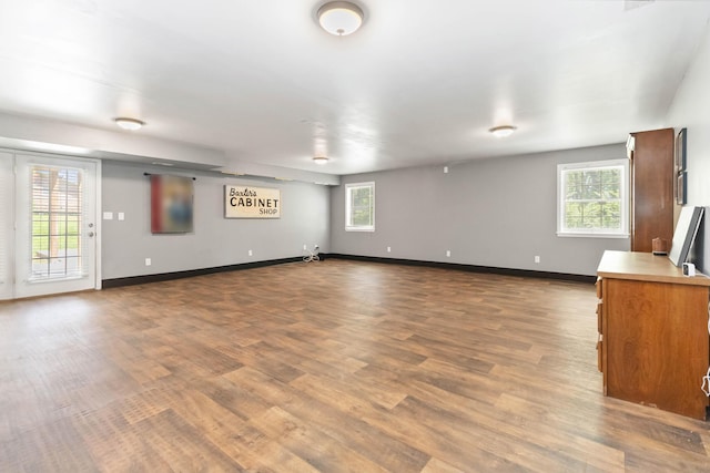 unfurnished living room with dark wood-style flooring, baseboards, and a healthy amount of sunlight