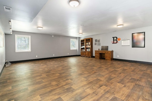 below grade area with plenty of natural light, baseboards, wood finished floors, and visible vents
