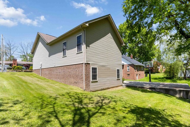 view of side of property featuring brick siding and a yard