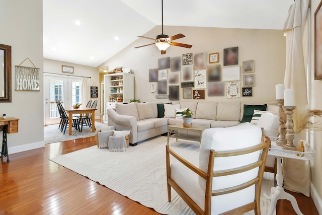 living room with baseboards, a ceiling fan, high vaulted ceiling, and hardwood / wood-style floors