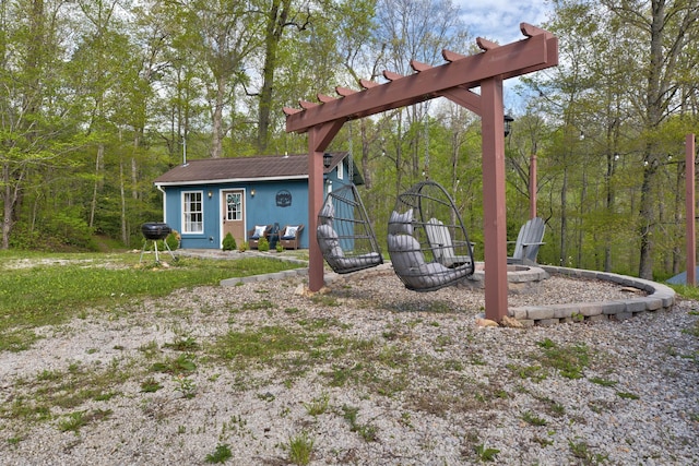 view of yard featuring an outbuilding, an outdoor fire pit, and a forest view