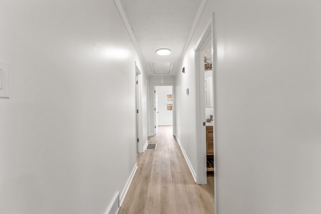 hallway featuring visible vents, ornamental molding, light wood-style floors, attic access, and baseboards