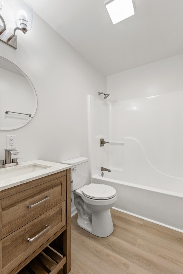 bathroom with shower / bathing tub combination, wood finished floors, vanity, baseboards, and toilet