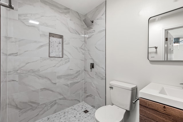 full bathroom with vanity, a tile shower, and toilet