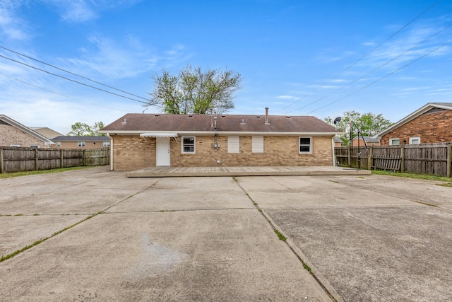 back of house with a fenced backyard, a patio, and brick siding