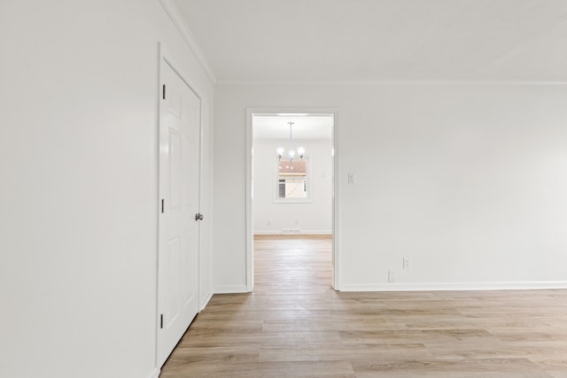 interior space featuring baseboards, ornamental molding, light wood finished floors, and a notable chandelier