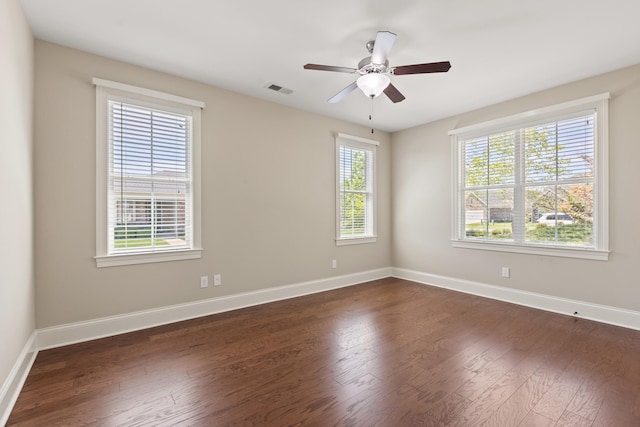 spare room with baseboards, ceiling fan, dark wood-style flooring, and visible vents