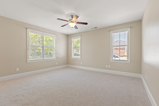 empty room with baseboards, plenty of natural light, light carpet, and ceiling fan
