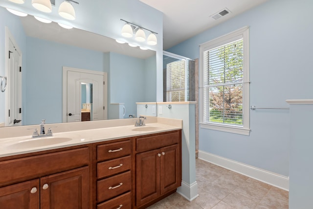 bathroom featuring a sink, a shower stall, double vanity, and visible vents