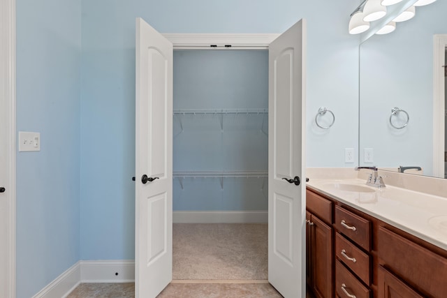 bathroom featuring double vanity, a sink, and a spacious closet