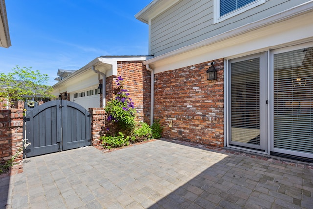 view of patio with an attached garage and a gate