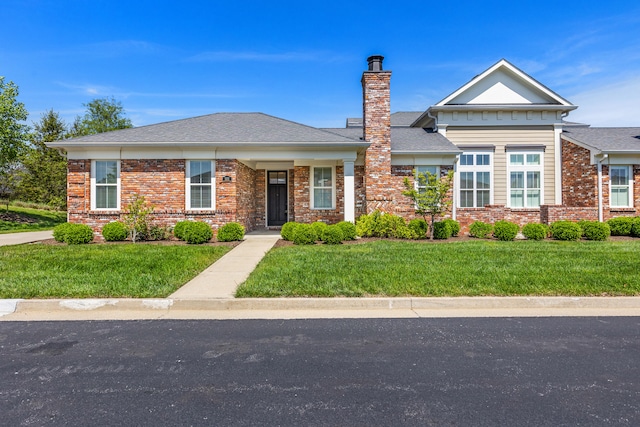 view of front of home with brick siding, a front lawn, and a chimney