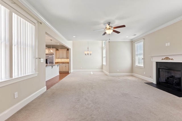 unfurnished living room with crown molding, light carpet, ceiling fan with notable chandelier, baseboards, and a fireplace with flush hearth