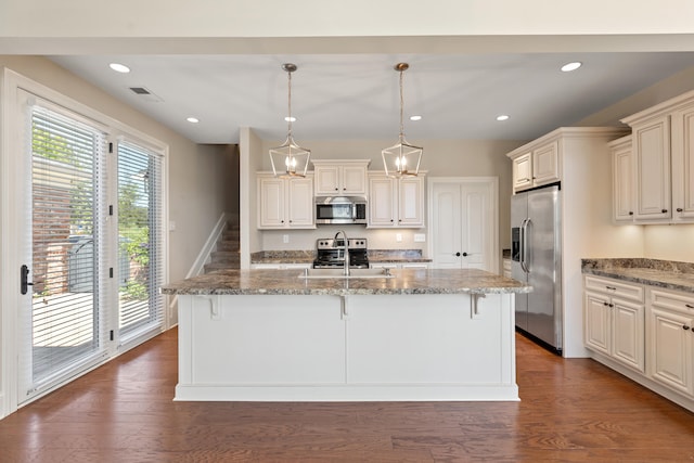 kitchen with a sink, appliances with stainless steel finishes, light stone countertops, and a breakfast bar