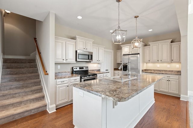 kitchen featuring appliances with stainless steel finishes, wood finished floors, a sink, recessed lighting, and an island with sink