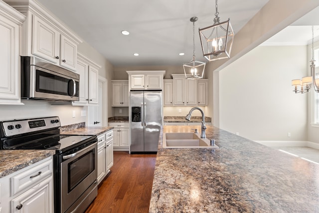 kitchen featuring recessed lighting, white cabinets, a sink, appliances with stainless steel finishes, and a notable chandelier