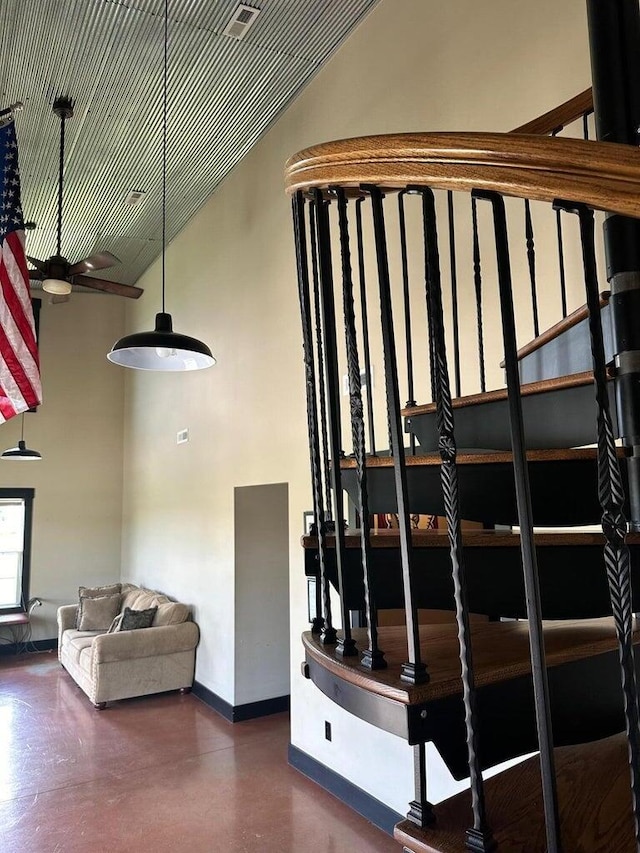 stairs with baseboards, ceiling fan, concrete flooring, and lofted ceiling
