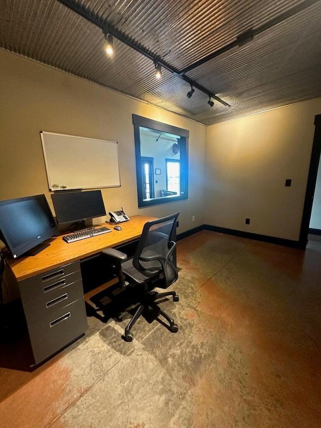 office space featuring baseboards, rail lighting, and concrete flooring