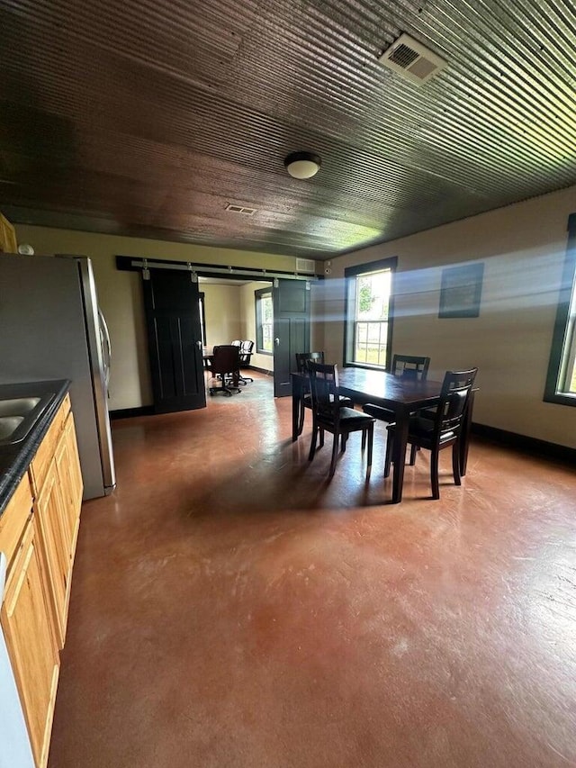 dining space featuring concrete flooring, visible vents, and a barn door