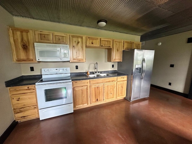 kitchen featuring white appliances, dark countertops, baseboards, and a sink