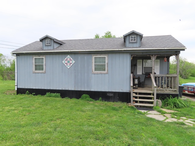 view of front of house with a porch, roof with shingles, and a front yard