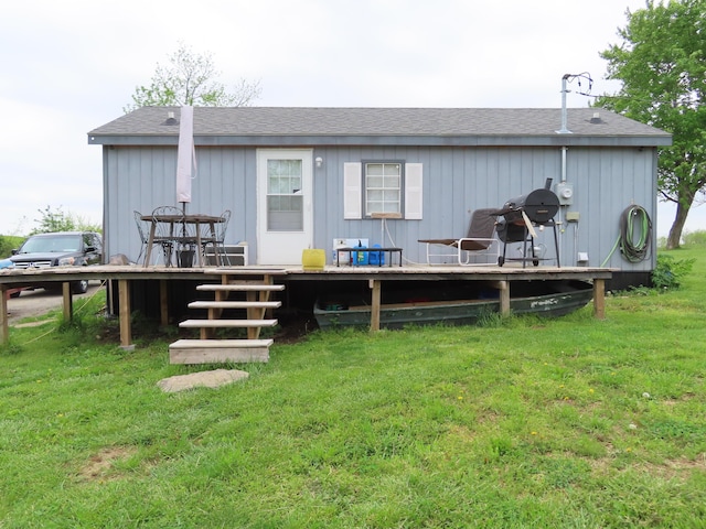 back of house featuring a lawn, a deck, and roof with shingles