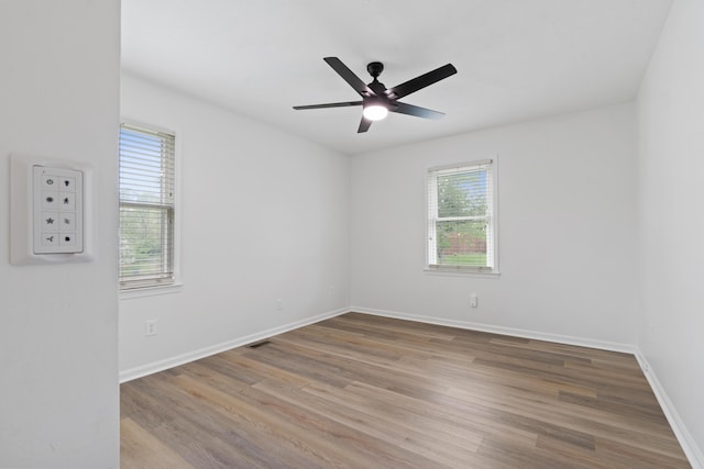 spare room featuring plenty of natural light, wood finished floors, and baseboards