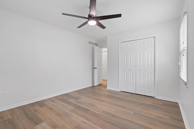 unfurnished bedroom with light wood-style flooring, baseboards, and a closet