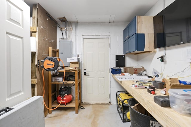 kitchen with electric panel, blue cabinetry, concrete floors, and light countertops