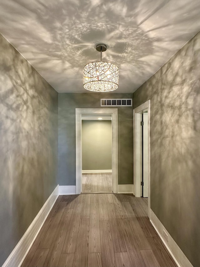 hall with baseboards, visible vents, and wood finished floors