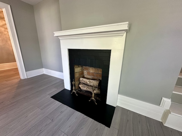 interior details featuring a fireplace with flush hearth, baseboards, and wood finished floors