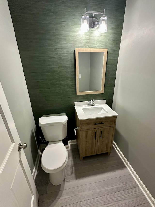 bathroom with baseboards, vanity, toilet, and wood finished floors