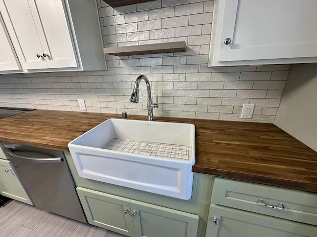 kitchen with tasteful backsplash, open shelves, stainless steel dishwasher, a sink, and butcher block counters